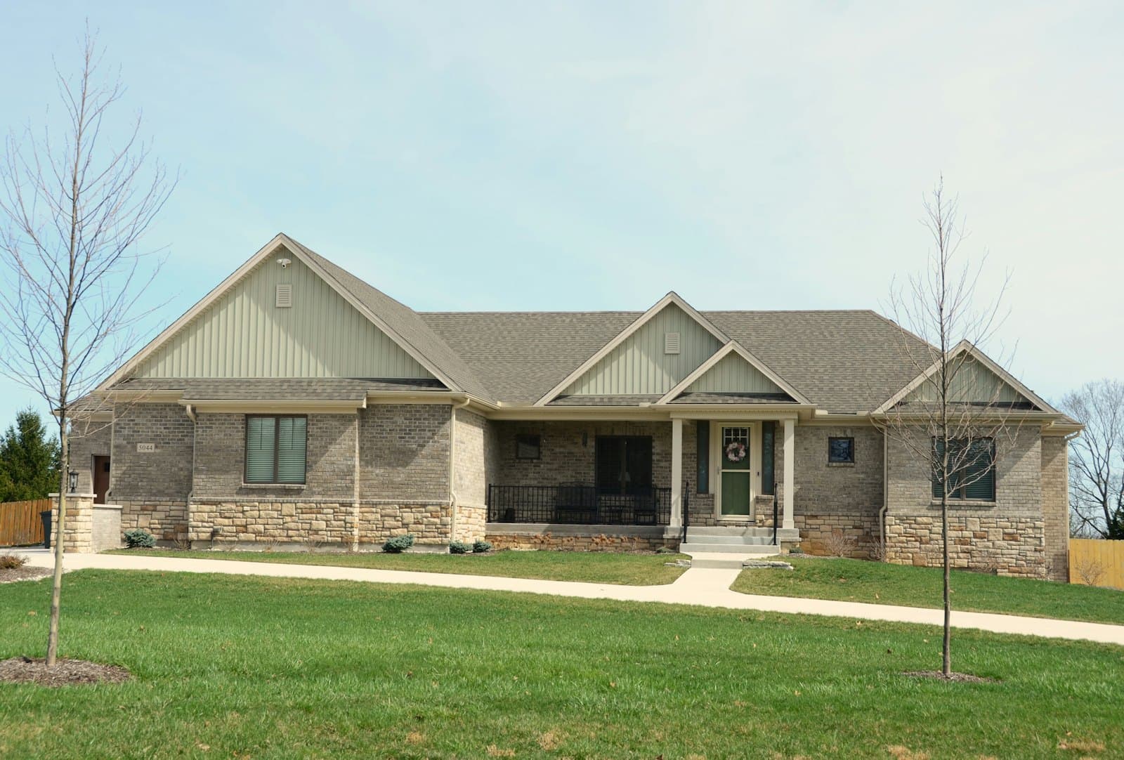 A brick and stone single-family house with a covered porch and a front lawn, photographed from the street.